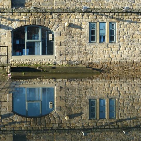 t20560: semi-abstract photo (reflection of Leeds building in still floodwater) by Ewart Shaw